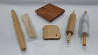 Full view of all items in the wooden kitchen set backing a group view of cutting boards, rolling pins, and wooden utensils.