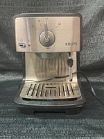 Front view of Krups espresso maker showing control dial, steam wand, and drip tray.