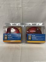 Photo of two new Power Fist tail lights in original packaging, showing front view with red lens and yellow and blue label.