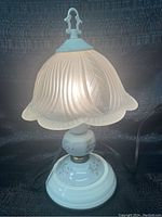 Photo of the lamp illuminated bright white light setting showing details of frosted floral glass shade and porcelain base