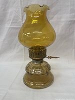 Full view of vintage amber glass oil lamp, showing the bulbous base and ruffled top chimney.