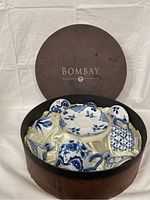 Full view of the set inside Bombay branded round box with satin lining, showing cups, covers and saucers.