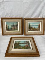 Three framed oil paintings, landscape scenes by Stan Tourangeau, arranged for display. Showcases the size and framing style.