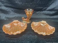 Three-piece lot with amber iridescent glass horn vase and two shell dishes on black fabric background.