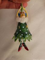 Close-up photo of Mini Cat Krinkles ornament, showing green star-shaped dress with white fur collar and red shoes