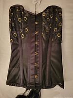 Front view of Corset Story black mesh overbust corset showing floral embroidery and metal front clasps.