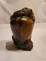 Front angle view of carved stone vase sculpture showing polished finish and natural stone color variations in brown, black, white, and maroon hues.