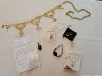Full lot showing jeweled belt, pendants, bracelet, rings, necklace, earrings, and note