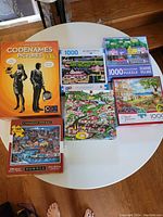 Overview of all jigsaw puzzles and the Codenames board game on round table.