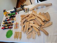 Overall view of the lot showing wooden tracks, bridges, and trains laid out on white surface