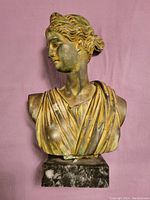Front view of the bust showing detailed face, hair, and draped garment with natural color patina on marble base.