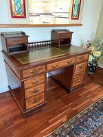 Front view of desk with green leather top, nine drawers and brass hardware