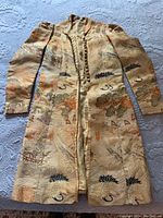 Full view of antique Japanese silk long coat laid flat, showing entire garment with patterned crane and floral design.