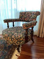 Full front view of barrel chair showing curved back, padded arms and turned wooden legs