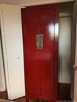 Front view of red lacquer tall narrow cupboard with closed doors