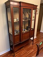 Side angled view of the wood china cabinet showing the glass doors and lower shelf