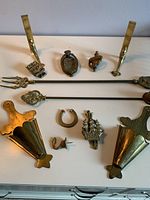 Overview of all brass items showing various shapes and functions including fireplace tools, wall hooks, sconces, and decorative plaques.