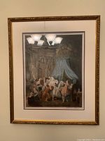 Framed colored etching showing a lively historical indoor scene with several figures in period costume, under a gold-tone decorative frame.