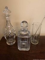 Wide shot of two vintage crystal decanters and a glass mixing pitcher with stirrer on a wood surface