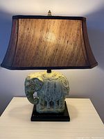 Front view of elephant-shaped lamp base with fabric shade illuminated.