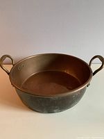 Full side view of large copper pan showing patina and handles
