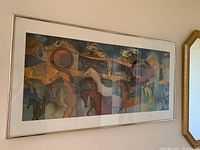 Full view of the rectangular framed colorful abstract print with horses in muted earth tones hung on a wall.