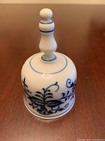 Front view of the porcelain dinner bell displaying the Blue Onion floral pattern and turned handle with blue accent rings.