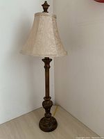 Full view of the lamp with beige patterned fabric shade and metal base detailing.