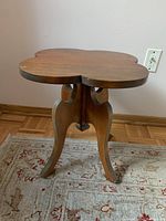 Front angle showing quatrefoil shape of tabletop with wood grain and cabriole legs.