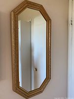 Full view of vertical octagonal mirror mounted on wall reflecting door and interior.