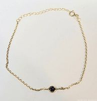 Full view of delicate gold plated sterling silver bracelet with small round amethyst gemstone centerpiece and spring ring clasp.