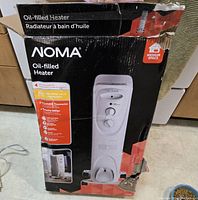 Photo of original box showing NOMA oil-filled heater branding and features: adjustable thermostat, portable design, suitable for medium space.