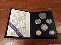Full view of the 1984 Canadian coin set in a black fold-out folder displaying six coins and a coin identification chart