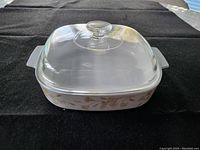 Vintage 2.5 Liter CorningWare casserole dish with clear glass lid shown on black cloth.