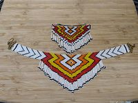 Top view of the necklace and hairpiece beadwork laid out on a wooden surface, showing full pattern and colors