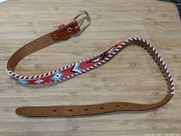 Full view of the leather belt showing the beaded design, buckle, and overall length.