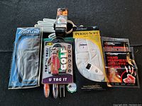 Image showing all golf accessories from above, laid out on black surface. Includes Mizuno Rainfit glove in original packaging, Titleist PermaSoft glove in packaging, two hand warmers, golf bag tag keychain, Tigger golf towel, two golf balls, glove holder, divot tool, ball marker and tees.