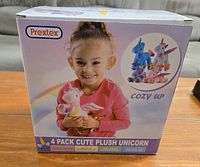 Front of box featuring a child holding a pink plush unicorn with the Prextex brand and 4 pack plush unicorn text