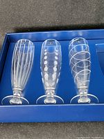 Set of three Mikasa Cheers etched pilsner beer glasses in blue box, showing the glasses upright and spaced.