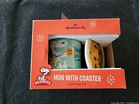 Front view of boxed ceramic Snoopy mug and cookie-shaped coaster in red Hallmark packaging.