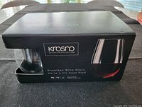 Black box packaging labeled Krosno featuring stemless wine glasses, with brand and volume information visible.