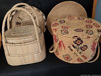 Front view of two woven baskets: one round with colored floral patterns and side handles, one rectangular with arched handles and lid.