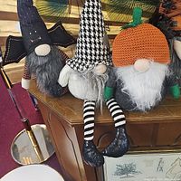 Photo showing five fall-themed gnomes with varied hats and beards placed on wooden furniture.