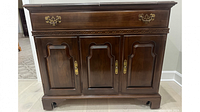 Front view of the Ethan Allen Georgian Court server showcasing dark cherry wood finish, brass handles, fretwork detailing, and three raised panel doors.
