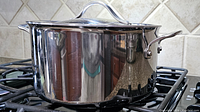 Side view of the polished stainless steel 8-quart stockpot showing the handle and reflective body on a stove.