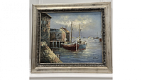 Framed canvas painting showing a harbor scene with boats and dock buildings in an ornate silver frame.