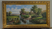 Front view of the framed canvas painting showing the full rural landscape scene with water, trees, flowers and house under cloudy sky, detailed ornate gold frame visible.
