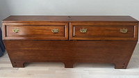 Front view of wooden headboard with two brass-handled cabinet doors, closed.