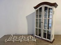 Wall cabinet and over-the-door hanger displayed side-by-side on table, showing overall appearance and finish.