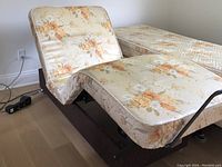 Photo showing the twin size adjustable bed partially raised at the upper and lower sections with floral patterned mattress and box spring, viewed from the side.